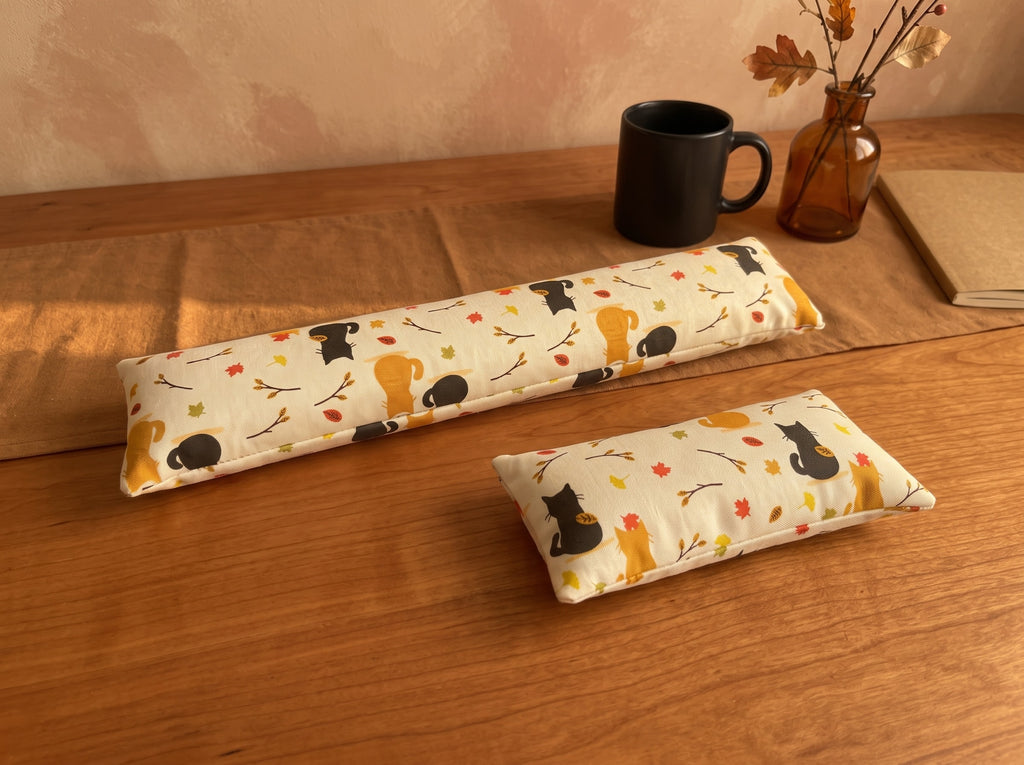 Autumn black cat keyboard and mouse wrist rests on a wooden desk with a black mug and autumn leaves