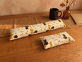 Autumn black cat keyboard and mouse wrist rests on a wooden desk with a black mug and autumn leaves