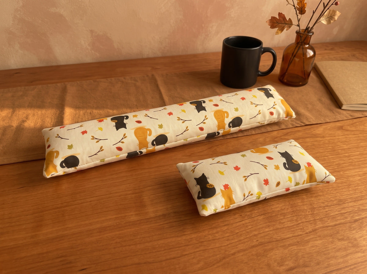 Autumn black cat keyboard and mouse wrist rests on a wooden desk with a black mug and autumn leaves
