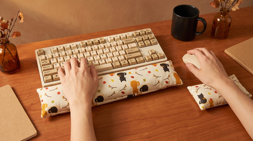 Hands on a keyboard and mouse resting on the autumn black cat wrist rests