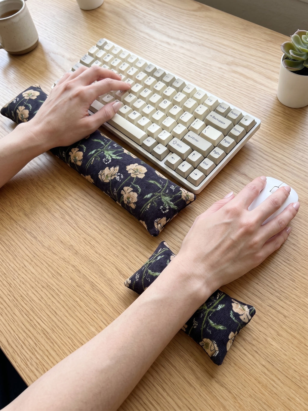 Hands on a keyboard and mouse resting on the black poppy corduroy wrist rests