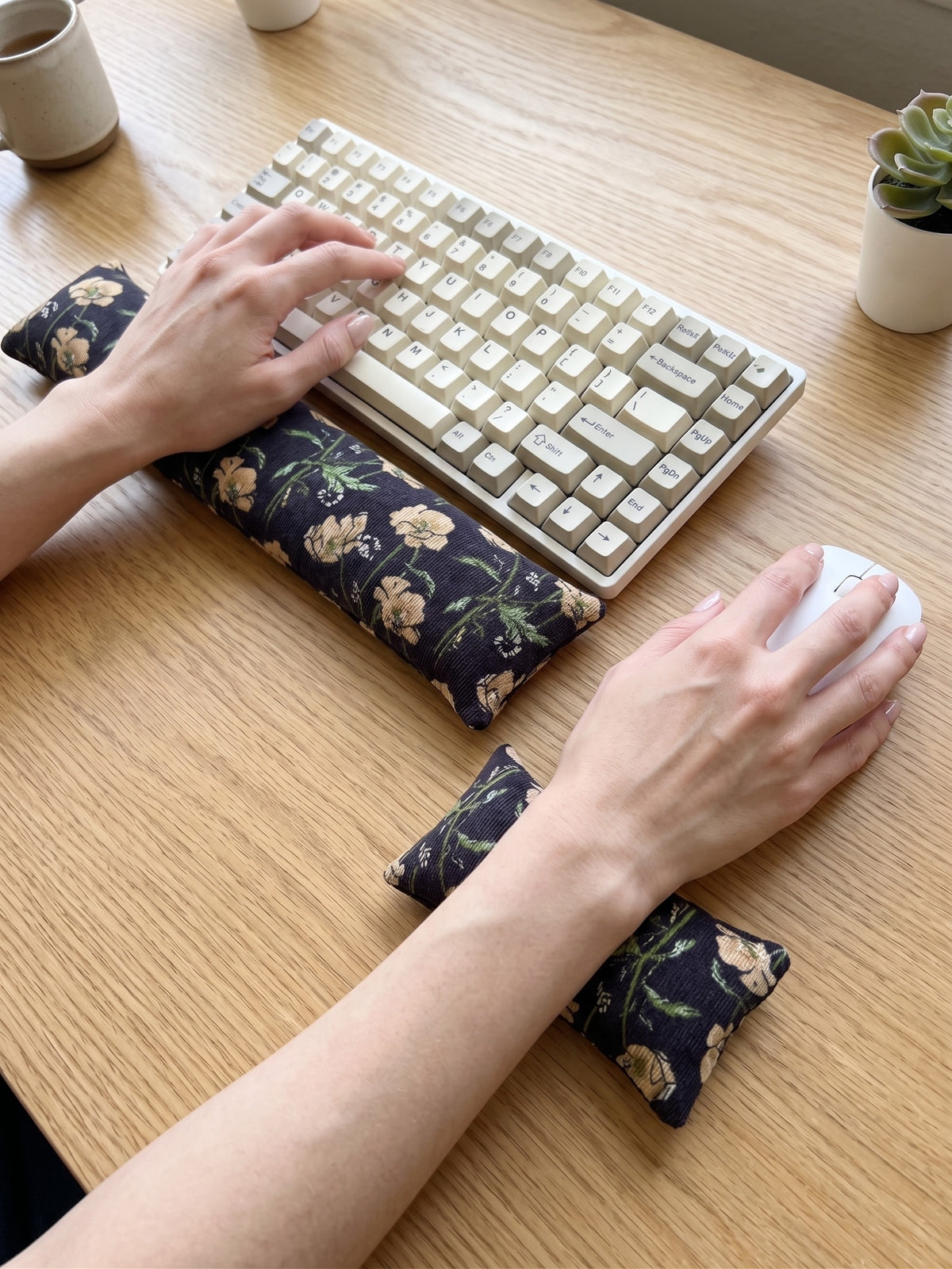 Hands on a keyboard and mouse resting on the black poppy corduroy wrist rests
