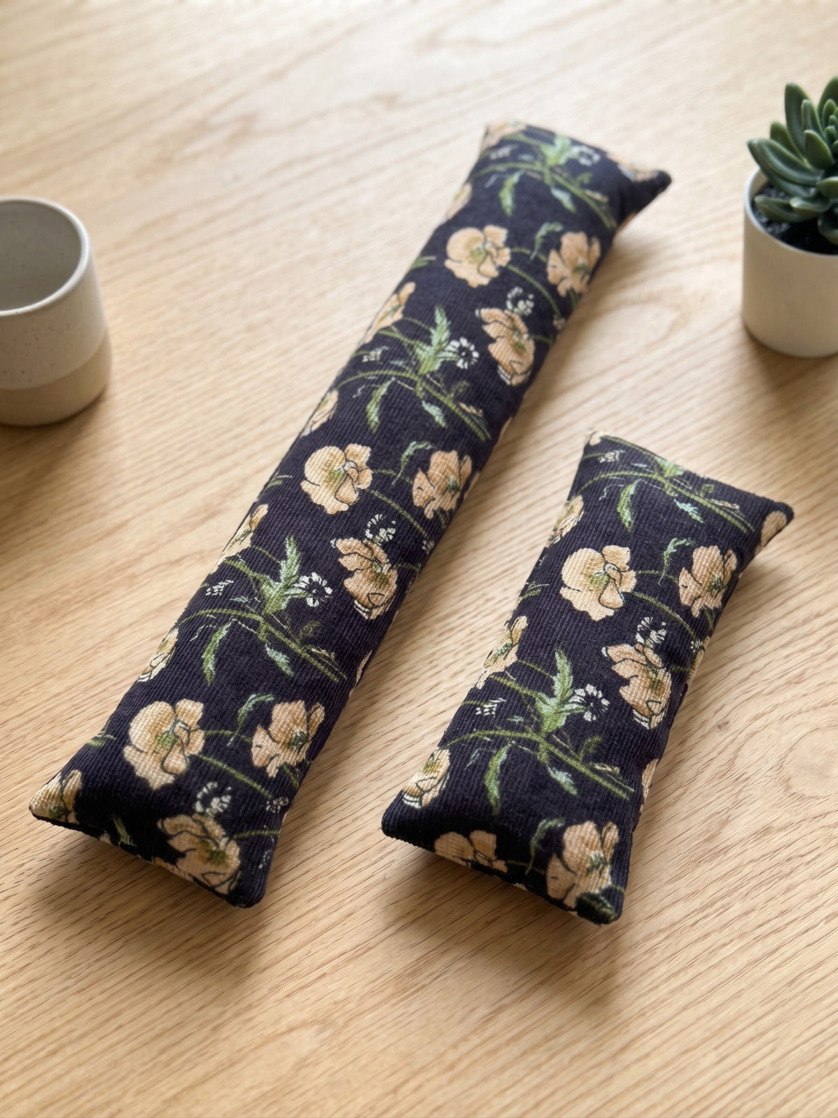 The two pieces of the black poppy corduroy set, a keyboard wrist rest and a mouse wrist rest
