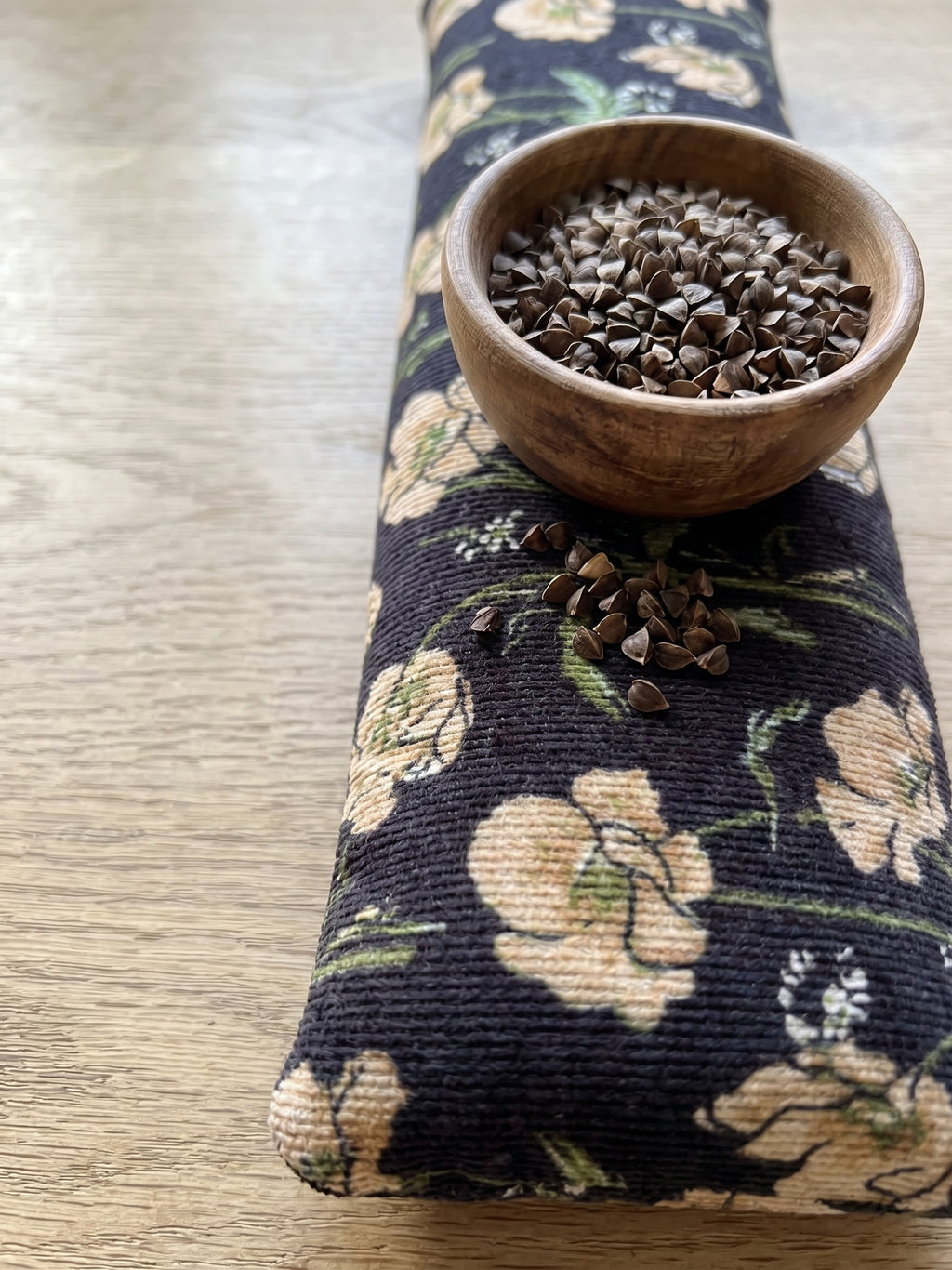 Black poppy corduroy wrist rest with a bowl of the buckwheat hulls used as filling
