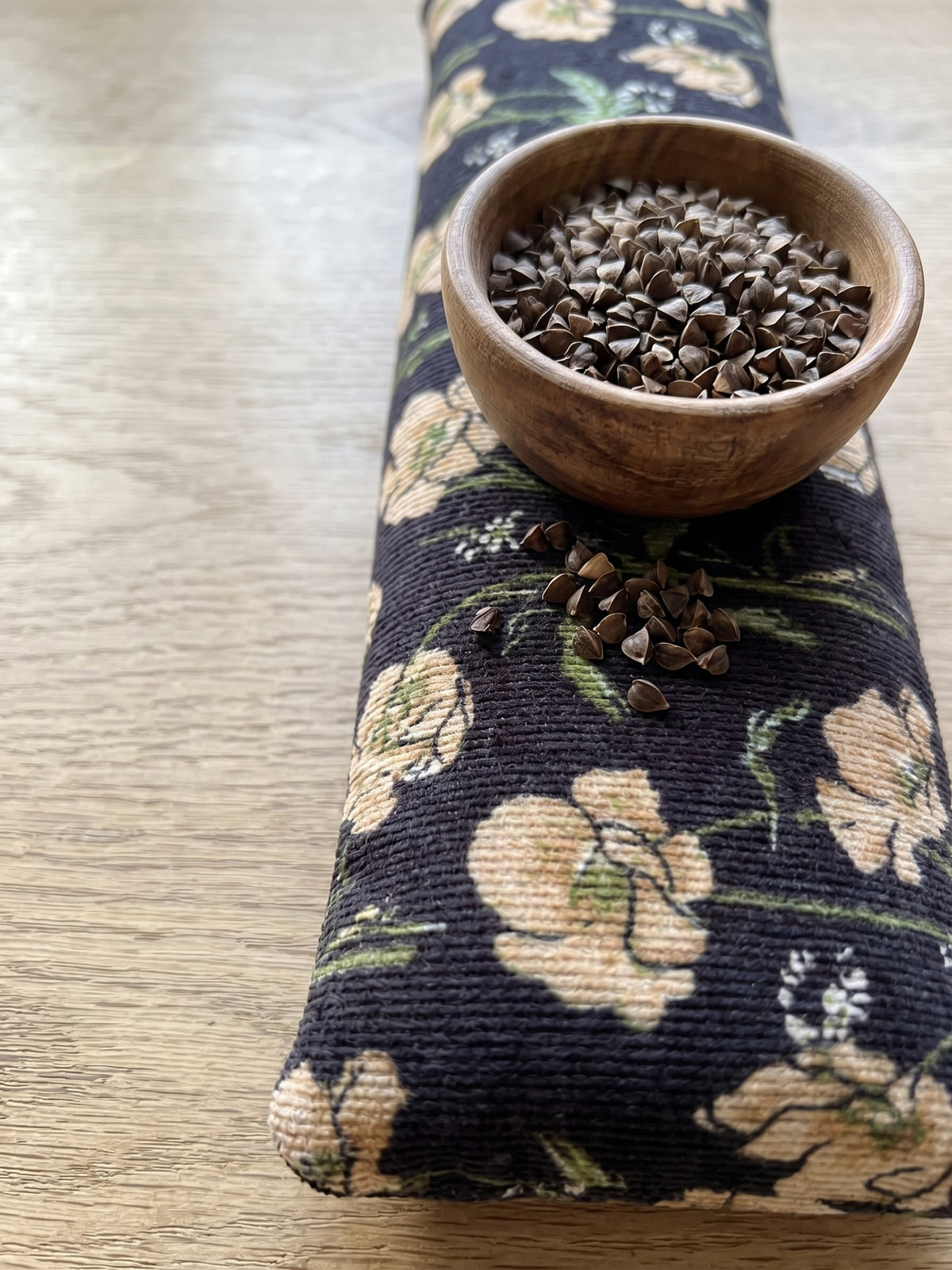 Black poppy corduroy wrist rest with a bowl of the buckwheat hulls used as filling