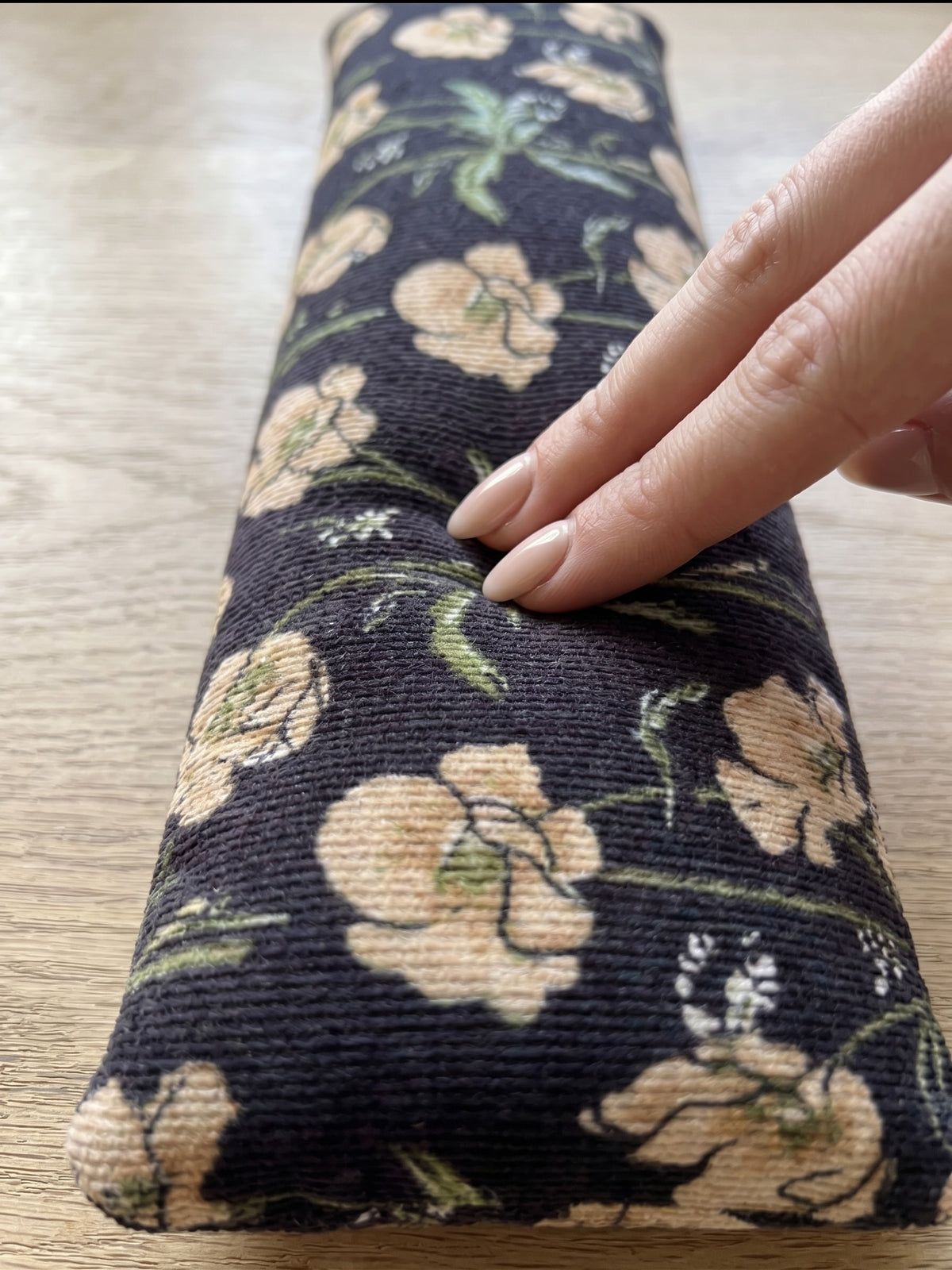 Fingers pressing into the black poppy corduroy wrist rest to show the buckwheat filling