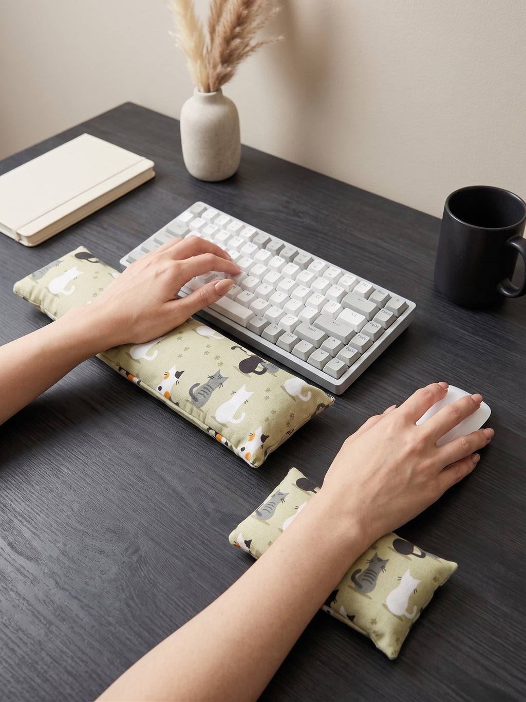 Hands on a keyboard and mouse resting on the sage green cat print wrist rests