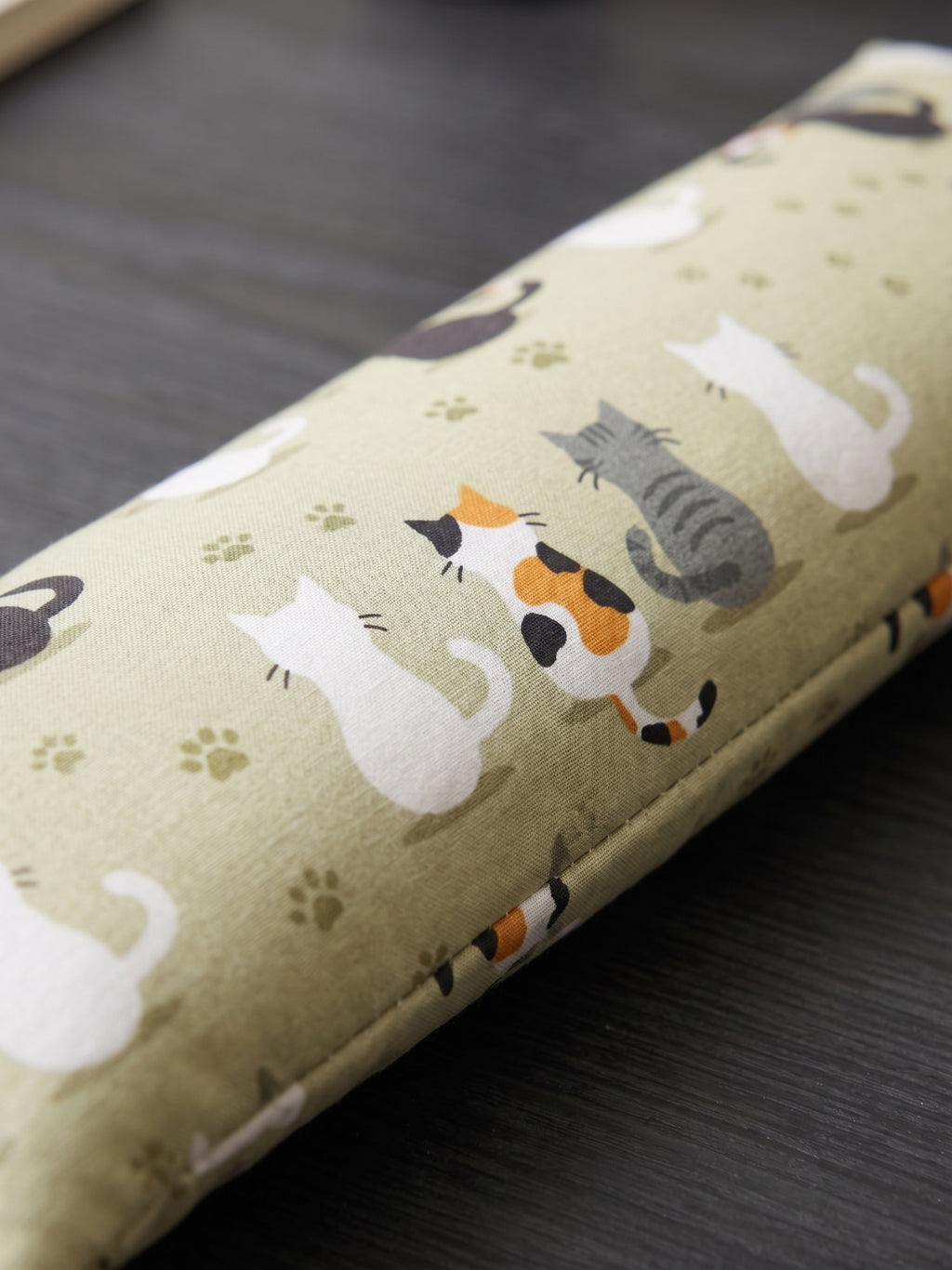 Close-up of calico, tabby and white cats with paw prints on sage green cotton
