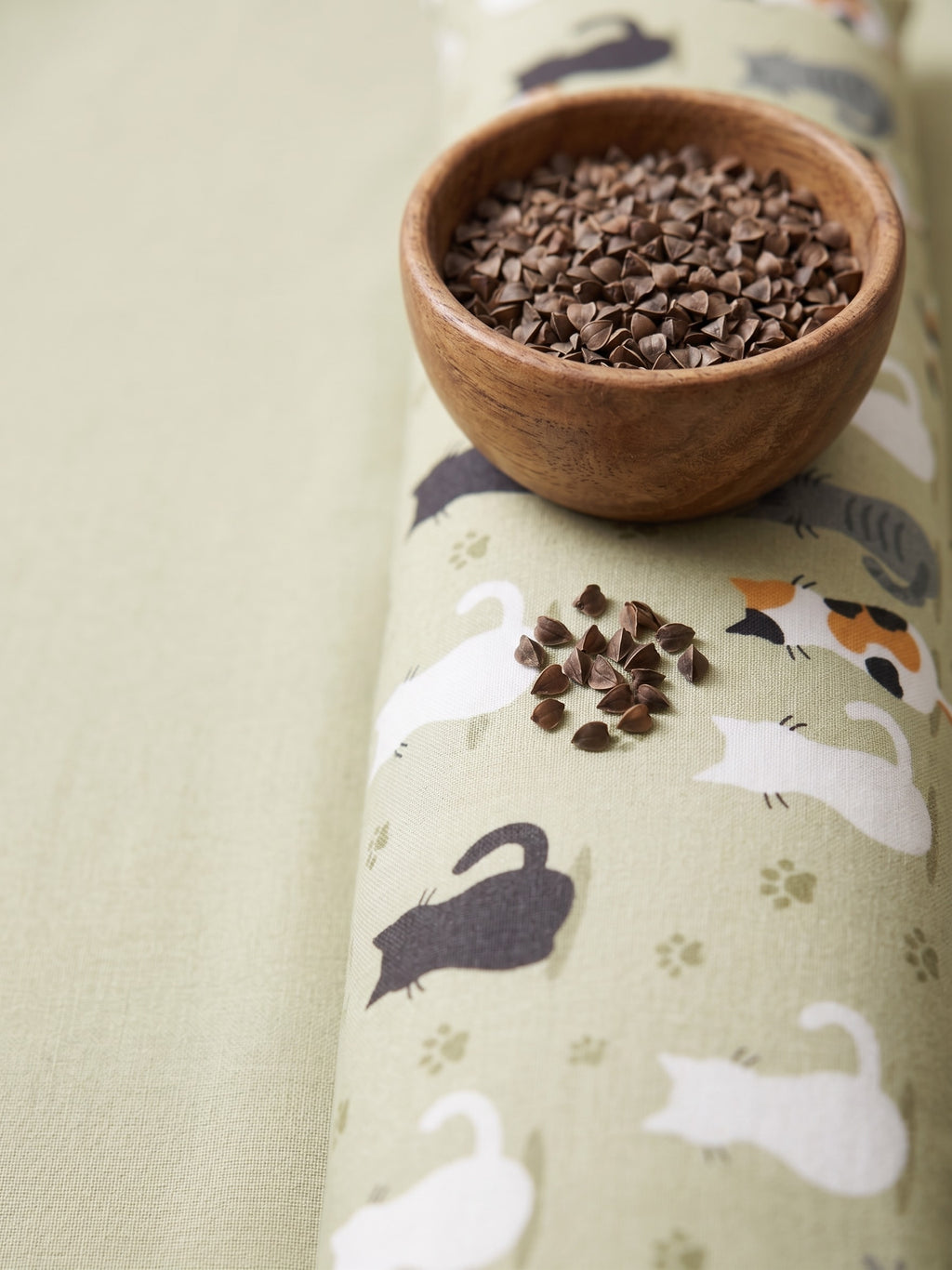 Sage green cat print wrist rest with a bowl of the buckwheat hulls used as filling