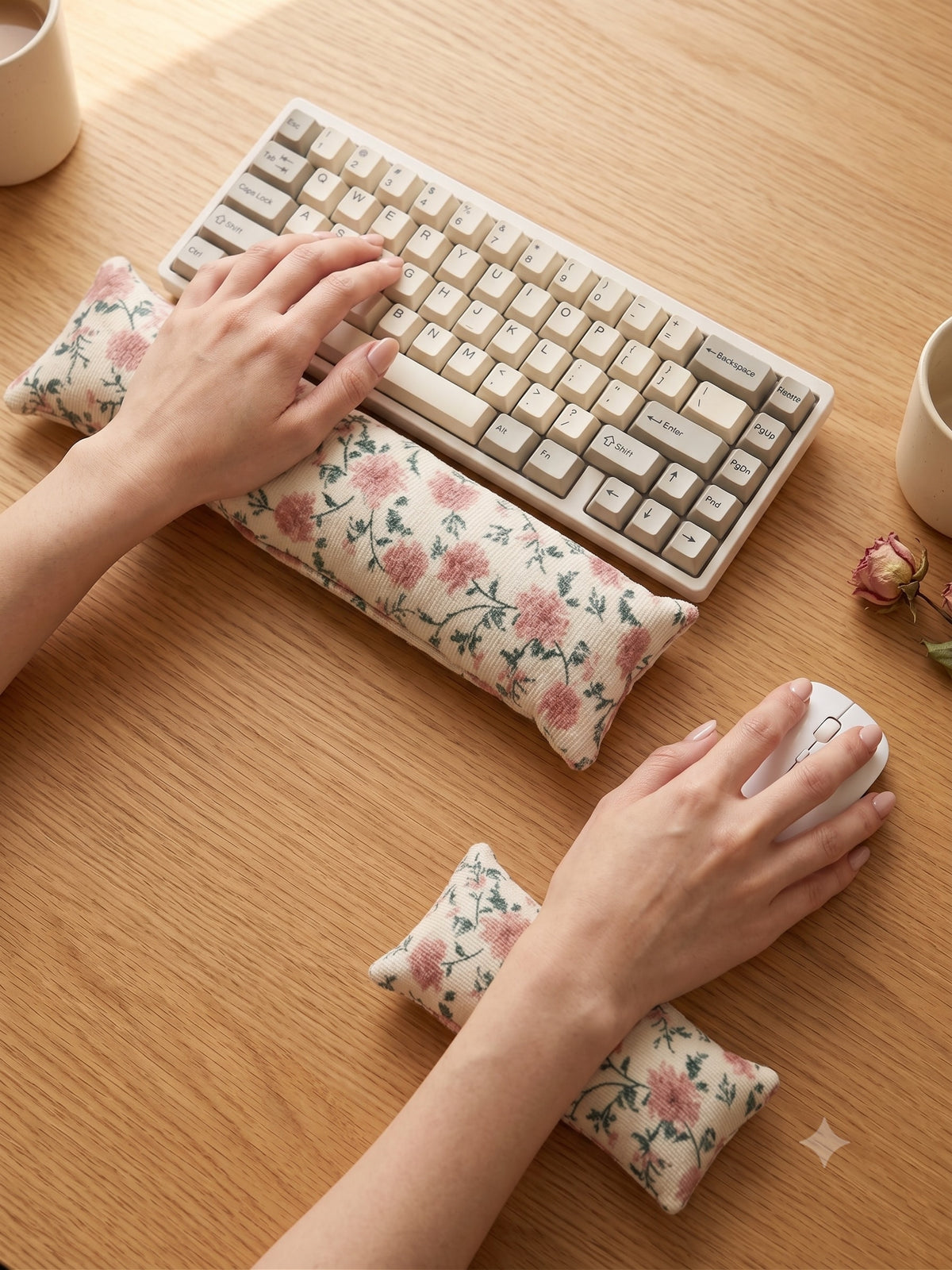 Hands on a keyboard and mouse resting on the chintz floral wrist rests