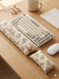 Cream floral corduroy keyboard and mouse wrist rests around a keyboard on a wooden desk