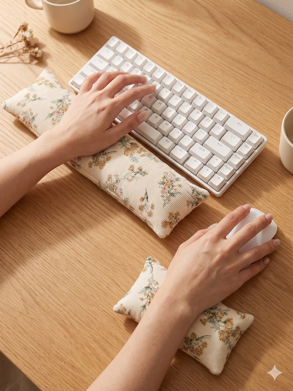 Hands on a keyboard and mouse resting on the cream floral corduroy wrist rests