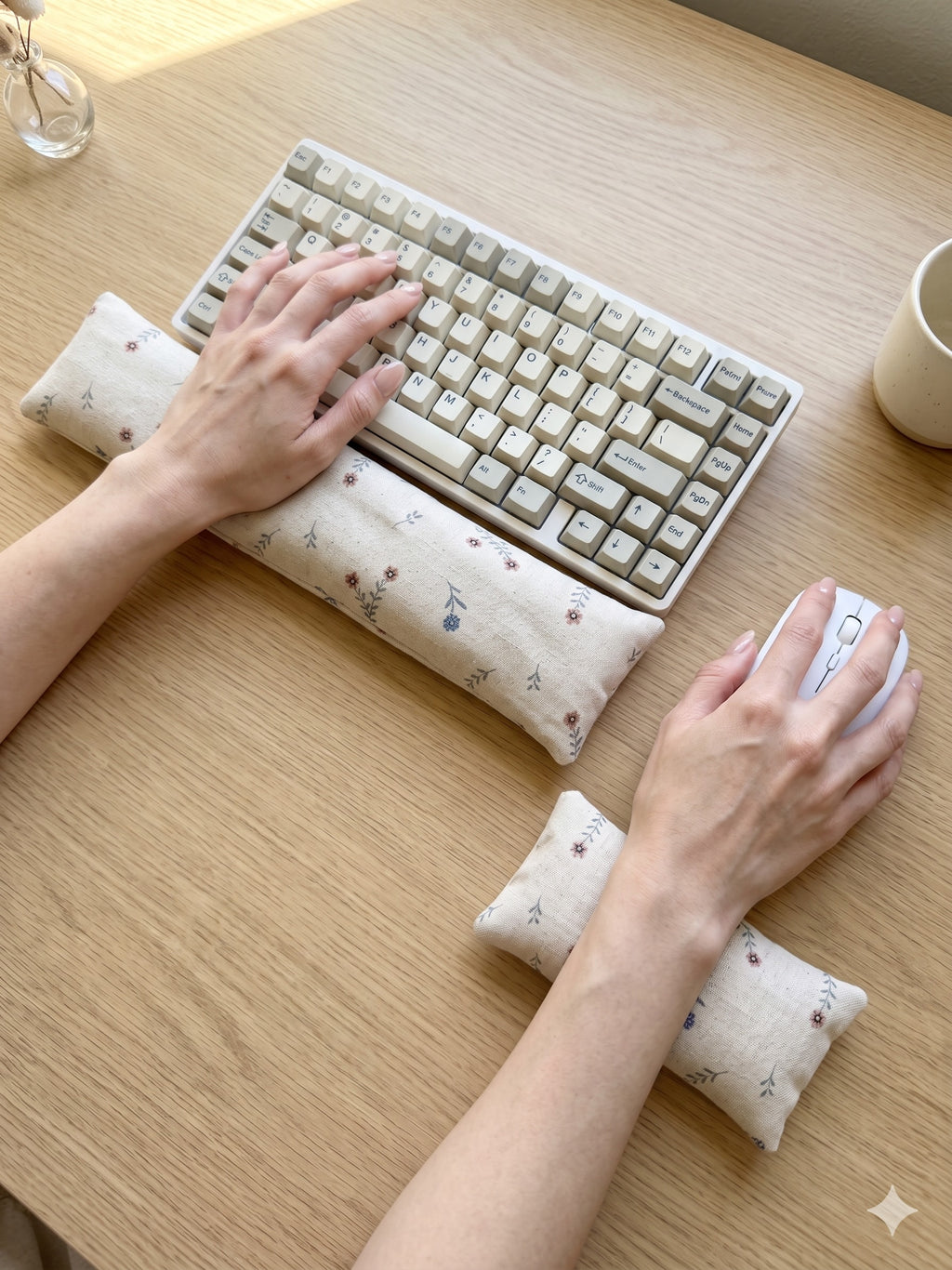 Hands on a keyboard and mouse resting on the ditsy floral linen wrist rests