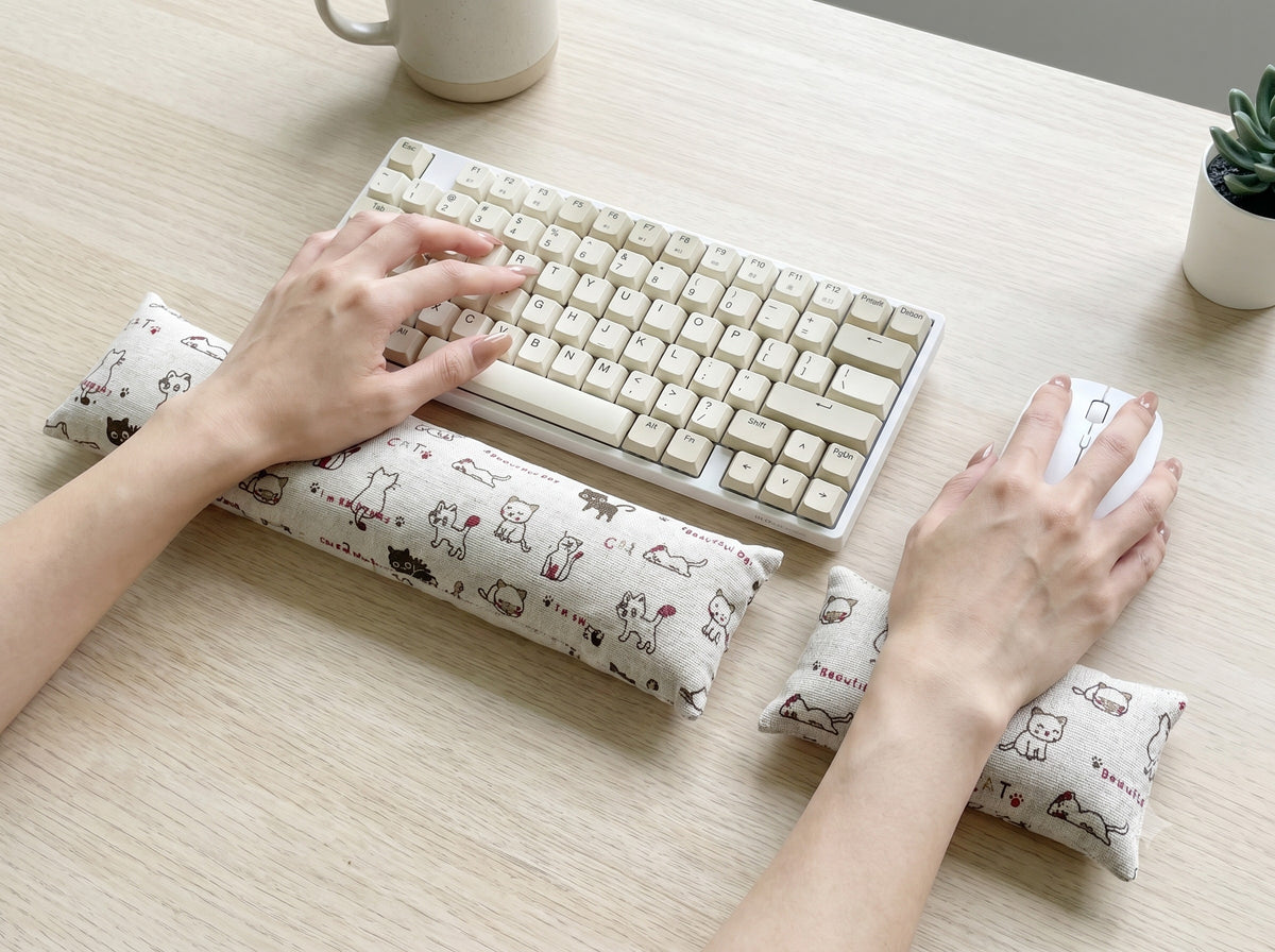 Hands on a keyboard and mouse resting on the natural doodle cat wrist rests