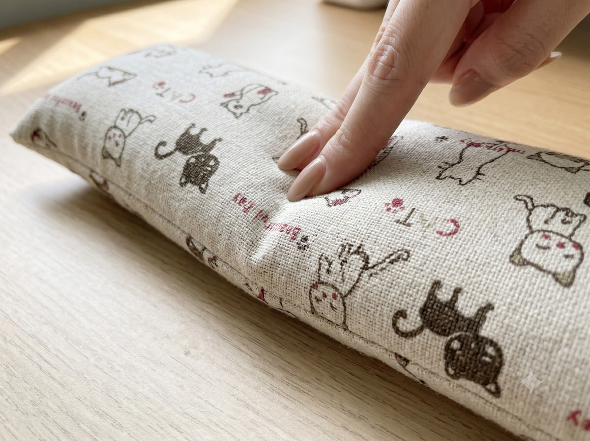 Fingers pressing into the natural doodle cat wrist rest to show the buckwheat filling