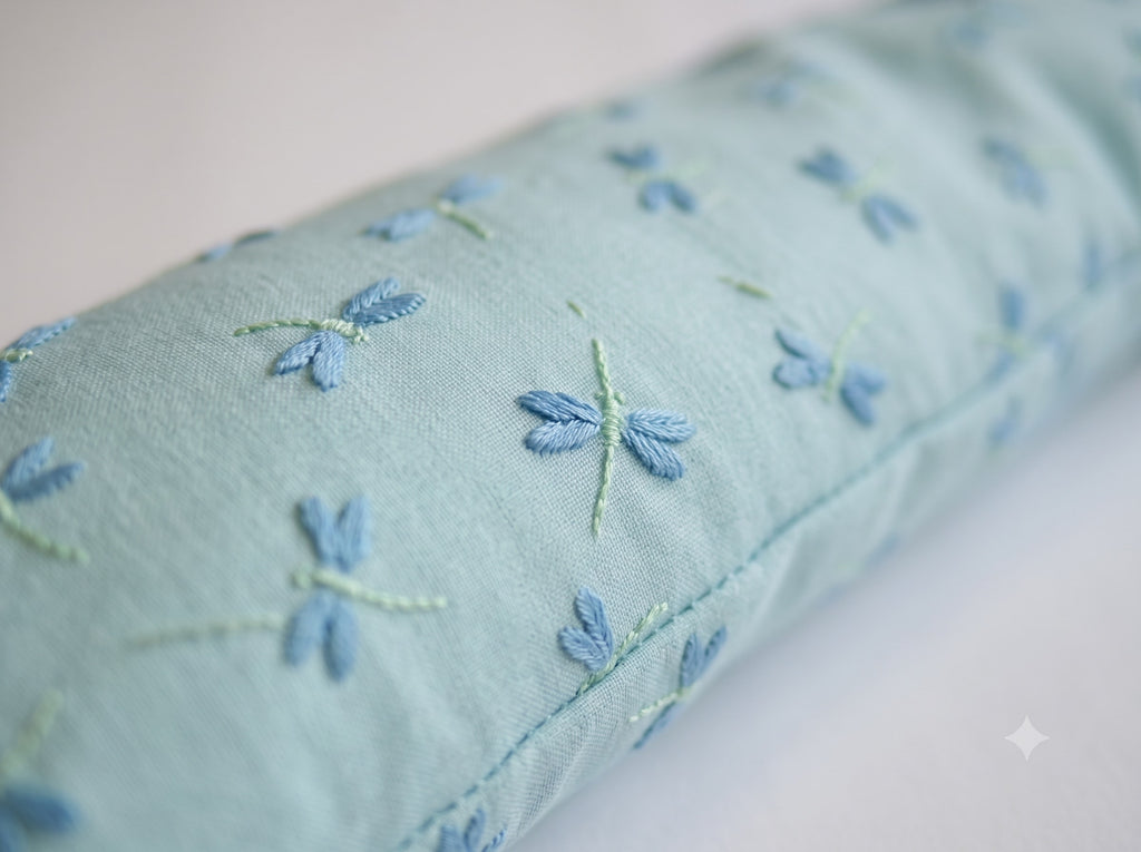 Close-up of the blue dragonflies embroidered on the pale aqua cover