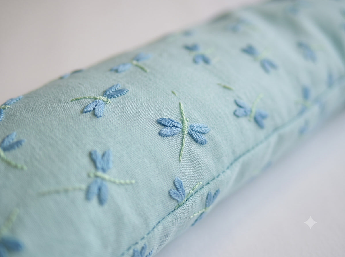 Close-up of the blue dragonflies embroidered on the pale aqua cover