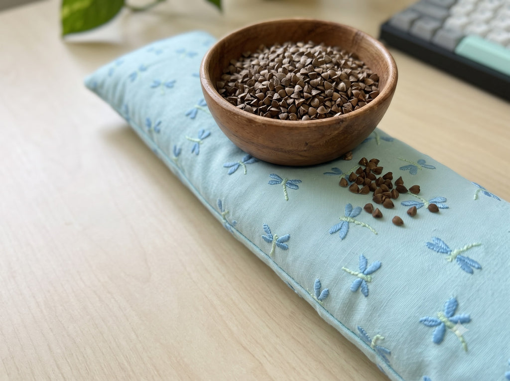 Embroidered dragonfly wrist rest with a bowl of the buckwheat hulls used as filling