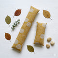 Yellow embroidered leaf keyboard and mouse wrist rests laid flat with autumn leaves and eucalyptus