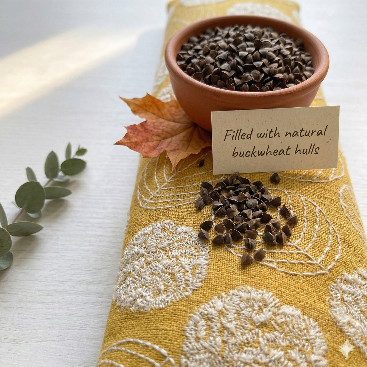 Yellow embroidered wrist rest with a bowl of buckwheat hulls and a card that reads filled with natural buckwheat hulls