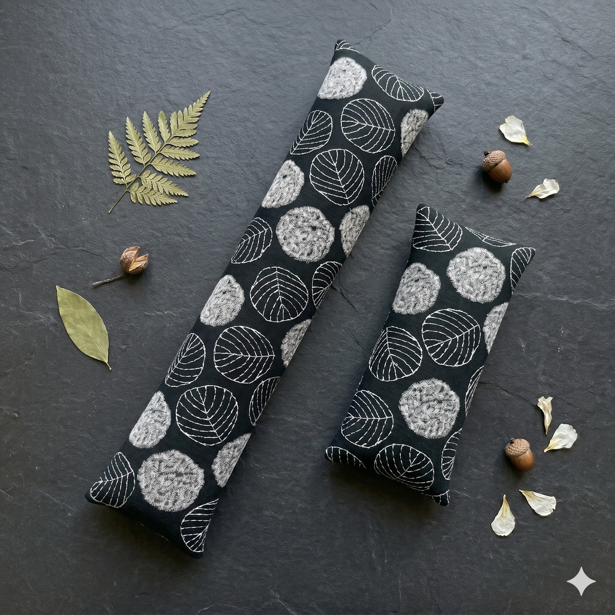 Black embroidered leaf keyboard and mouse wrist rests on dark slate with a fern