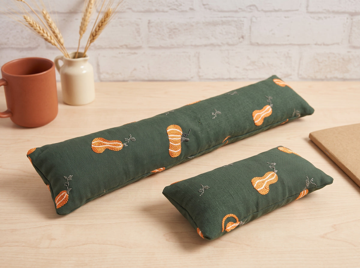 Forest green embroidered pumpkin keyboard and mouse wrist rests on a light wood desk