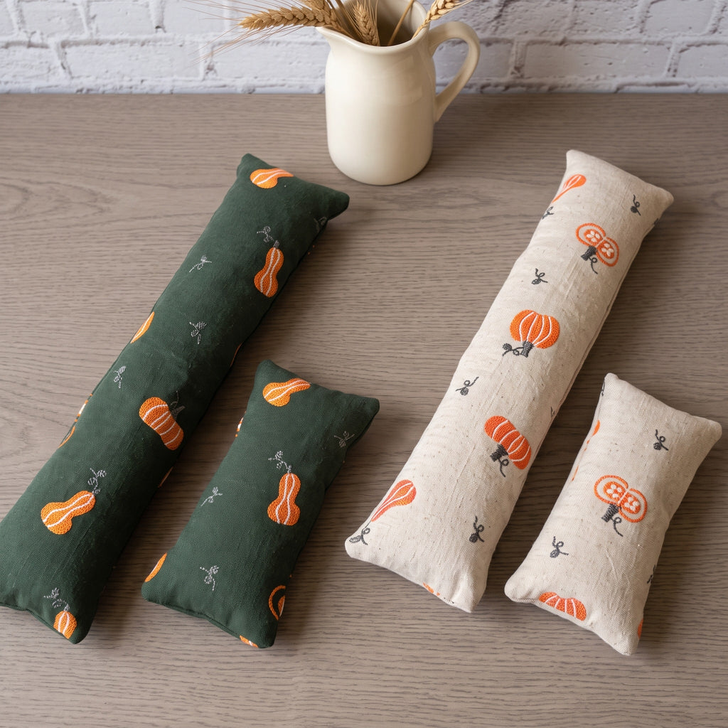 Embroidered pumpkin wrist rest sets in forest green and cream side by side