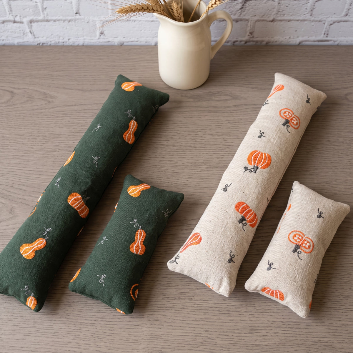 Embroidered pumpkin wrist rest sets in forest green and cream side by side