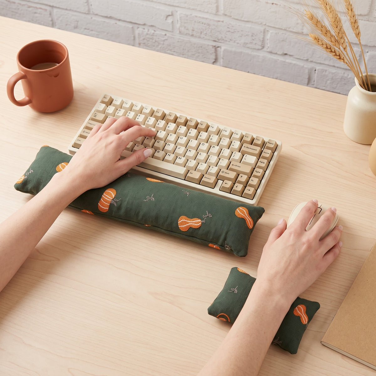 Hands on a keyboard and mouse resting on the forest green pumpkin wrist rests