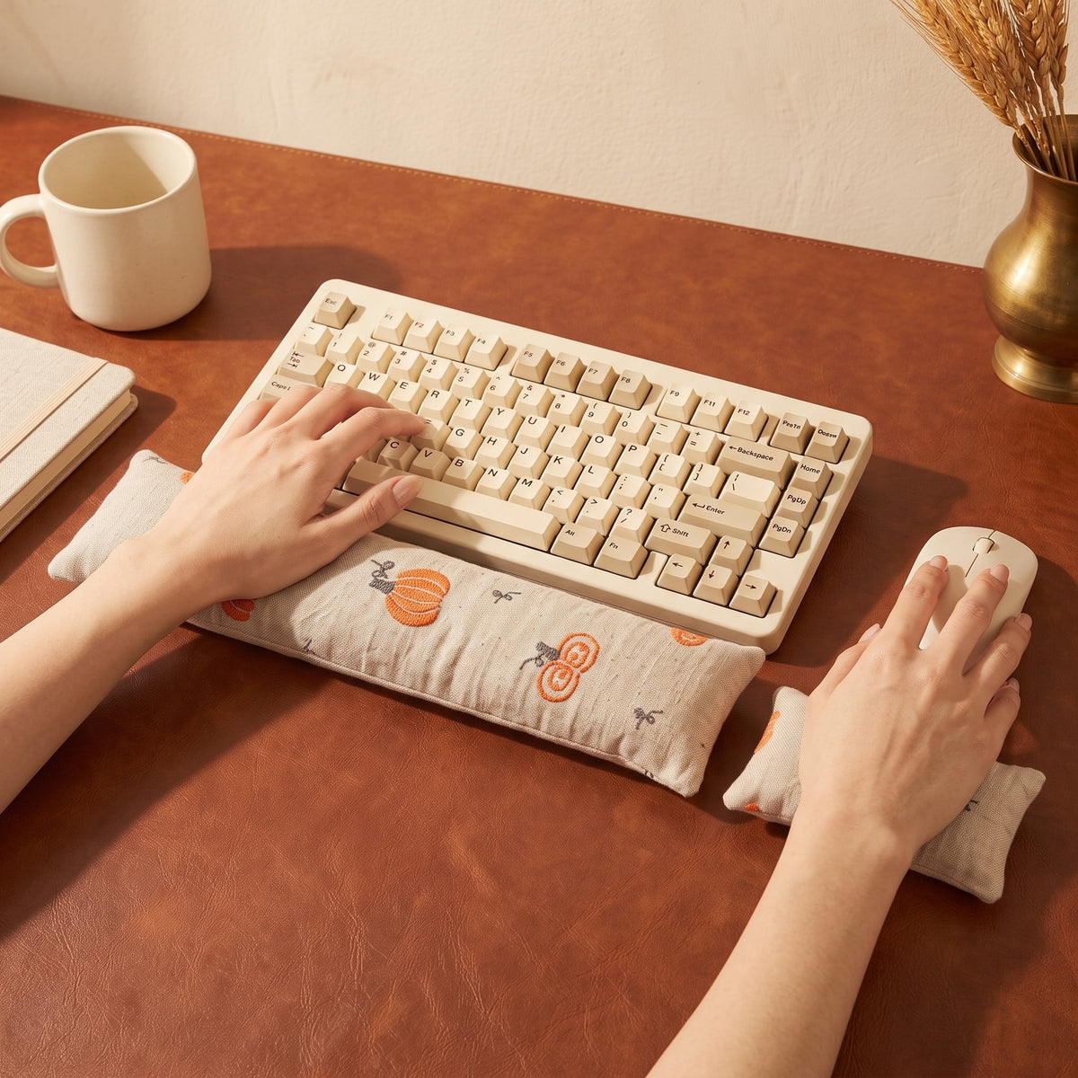 Hands on a keyboard and mouse resting on the cream pumpkin wrist rests