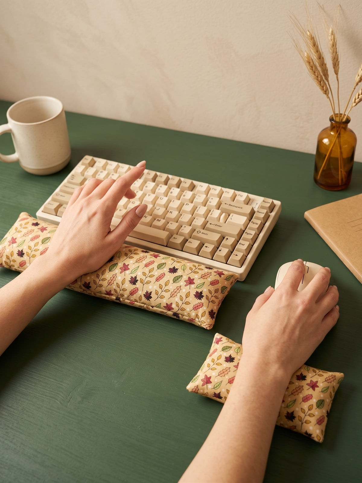 Hands on a keyboard and mouse resting on the fall maple leaf wrist rests