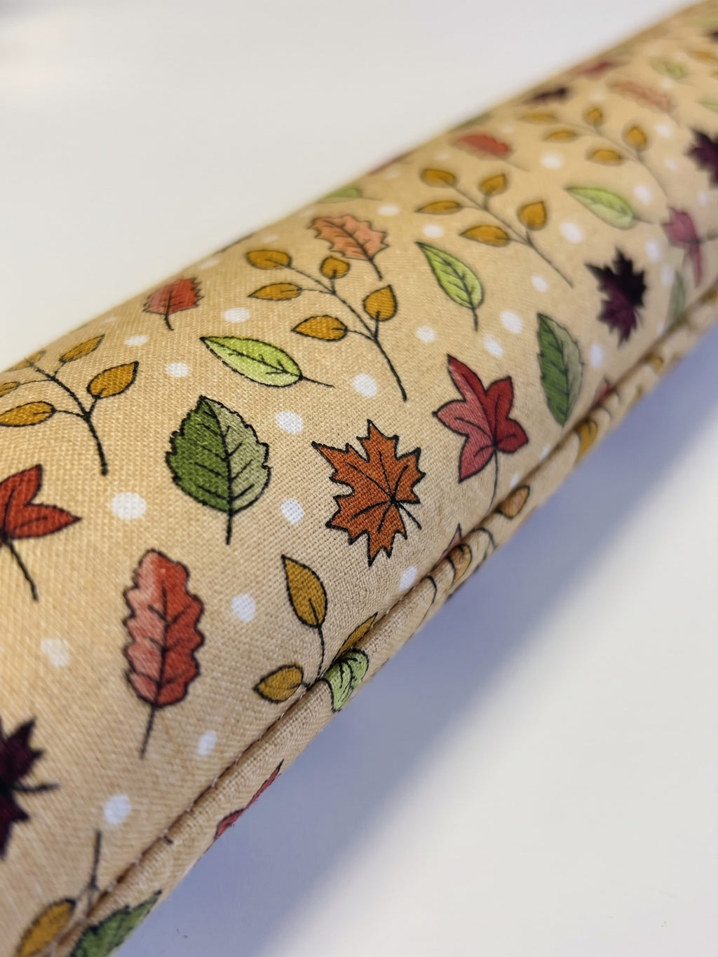 Close-up of maple and oak leaves in gold, orange, red and olive on cream cotton