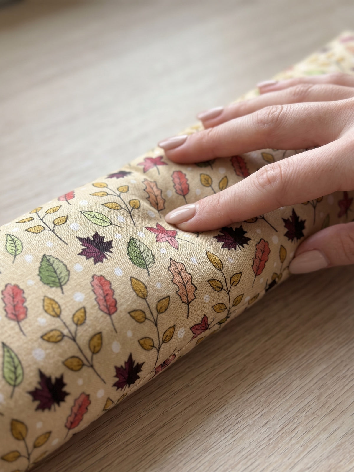 Hand pressing into the fall maple leaf wrist rest to show the buckwheat filling