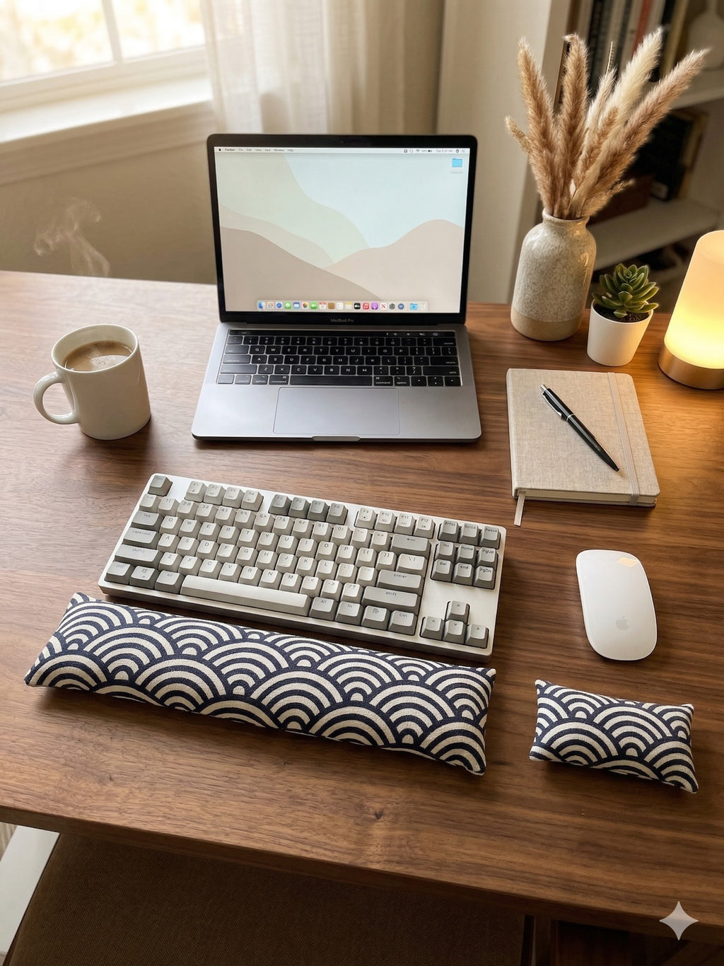Geometric arc wrist rest set in front of a keyboard on a desk with a laptop and notebook