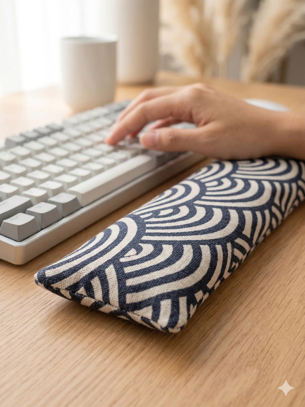 Hand typing on a keyboard above the geometric arc wrist rest