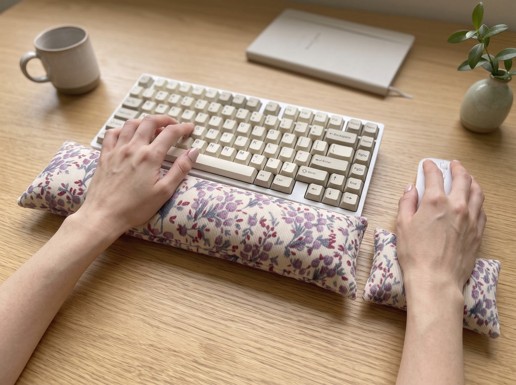 Hands on a keyboard and mouse resting on the lilac floral corduroy wrist rests