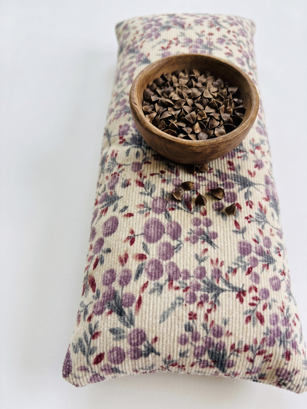 Lilac floral corduroy wrist rest with a bowl of the buckwheat hulls used as filling