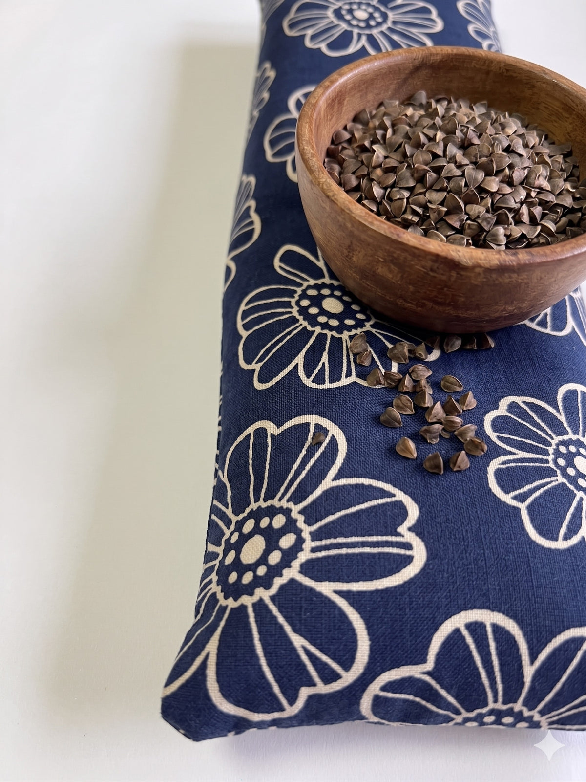 Navy daisy wrist rest with a bowl of the buckwheat hulls used as filling