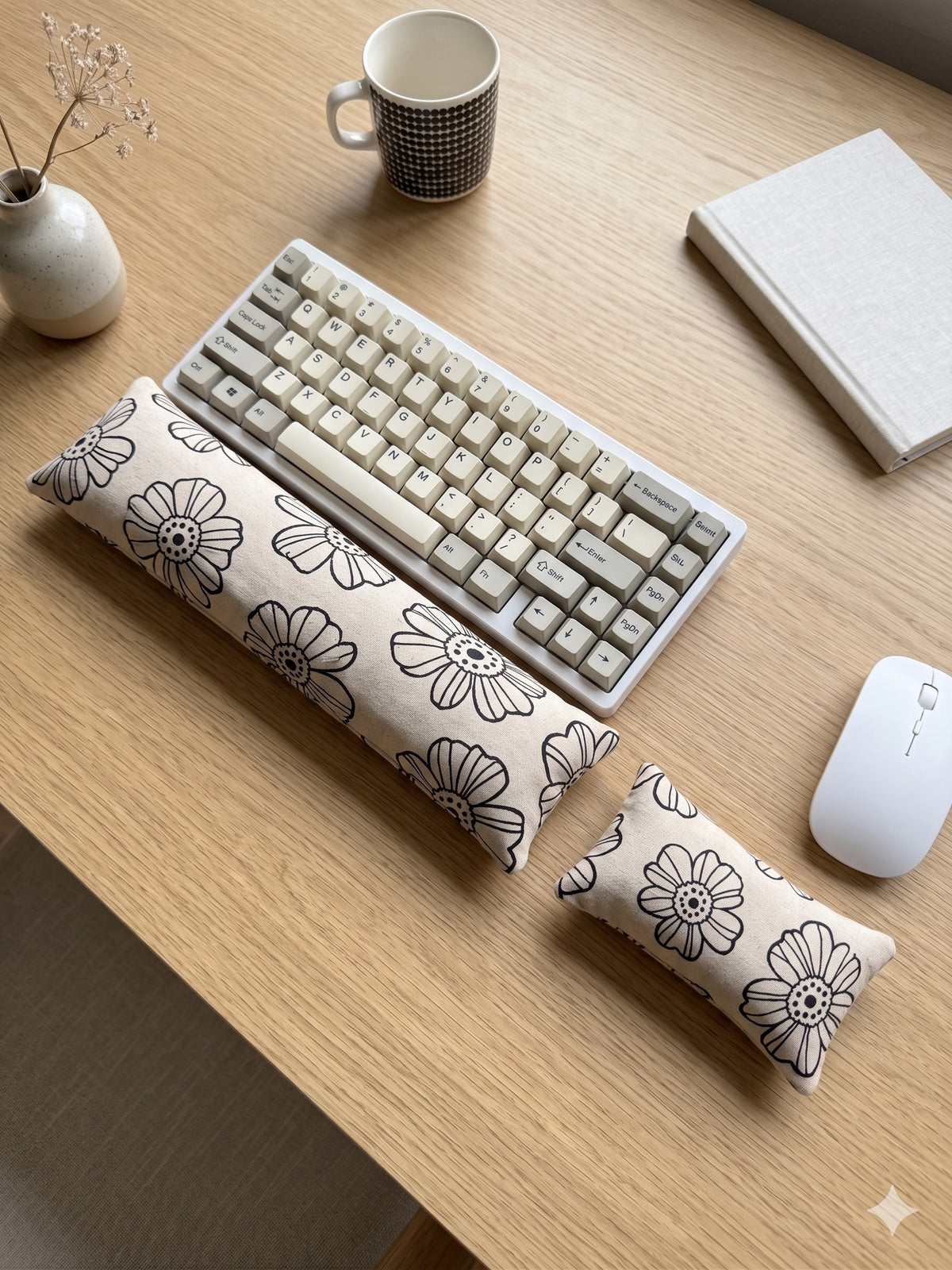Cream line art daisy keyboard and mouse wrist rests around a keyboard on a wooden desk