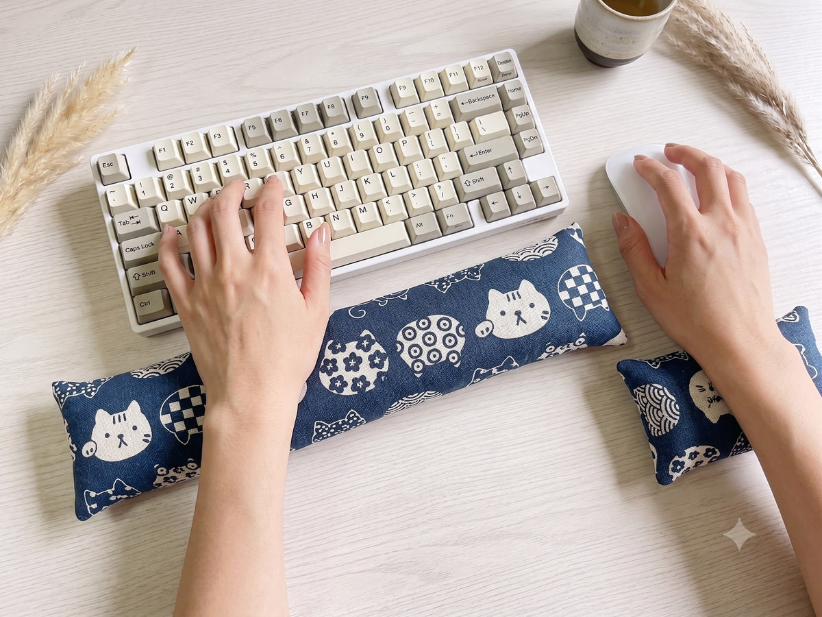 Hands typing on a keyboard above the blue lucky cat wrist rest, with the matching mouse rest