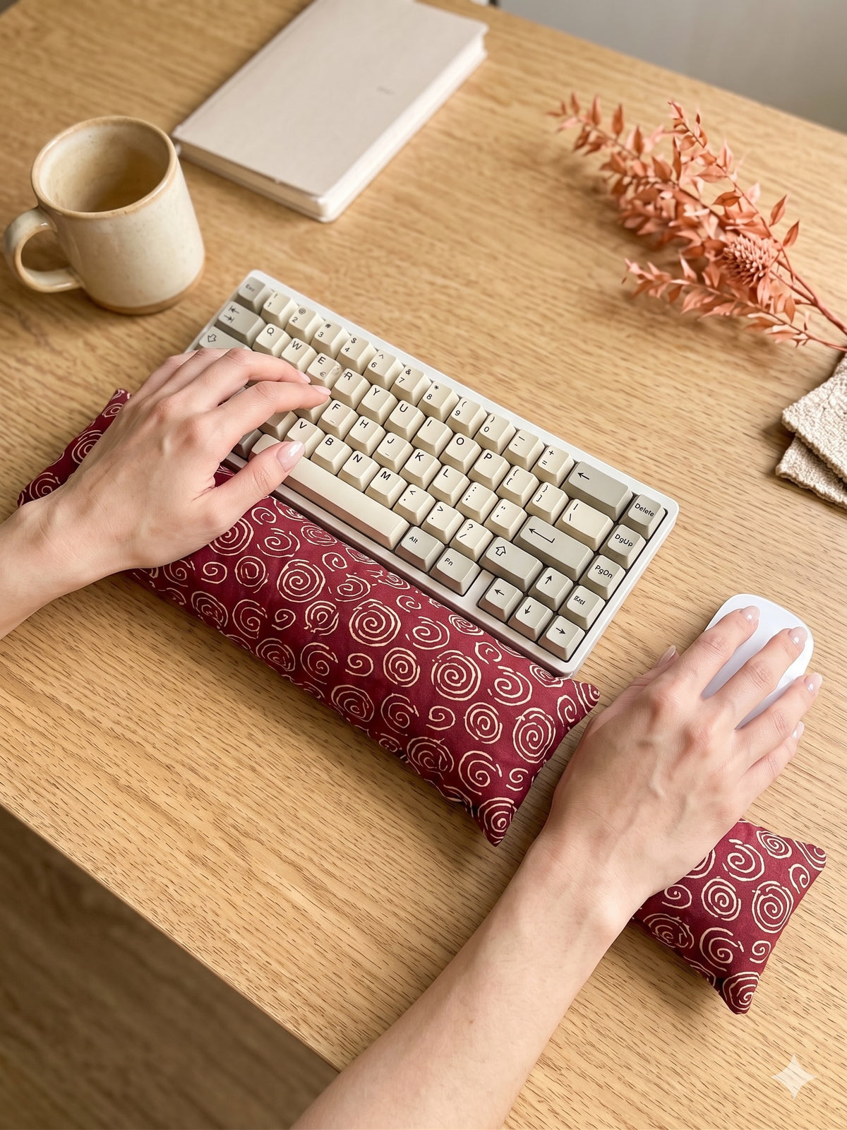 Hands on a keyboard and mouse resting on the red spiral wrist rests