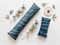 Blue mudcloth pillow velvet keyboard and mouse wrist rests laid flat with sprigs of greenery