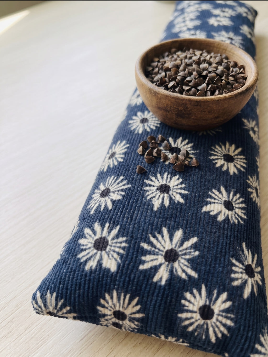 Navy daisy corduroy wrist rest with a bowl of the buckwheat hulls used as filling