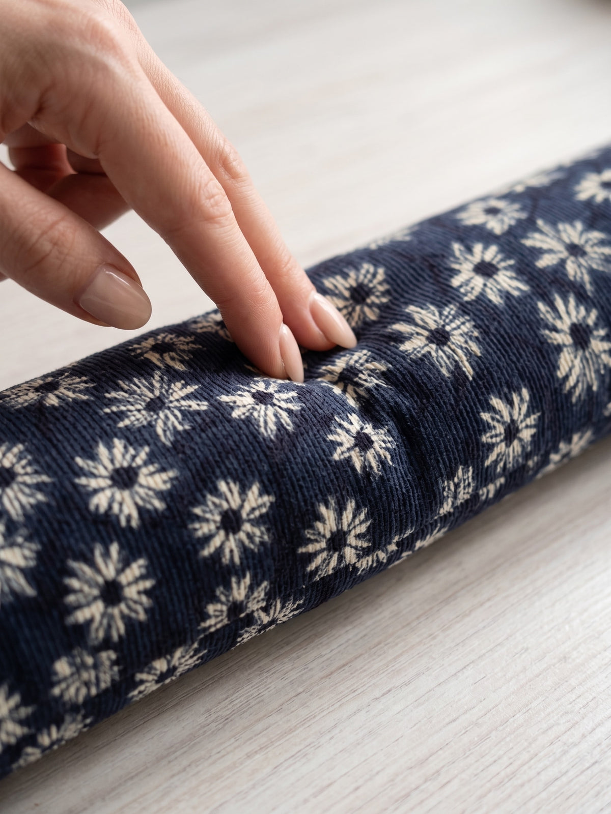 Fingers pressing into the navy daisy corduroy wrist rest to show the buckwheat filling