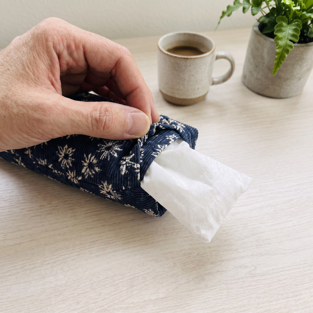 Hand sliding the white inner bag of buckwheat hulls out of the navy daisy corduroy cover