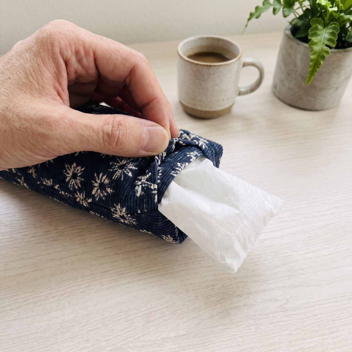 Hand sliding the white inner bag of buckwheat hulls out of the navy daisy corduroy cover