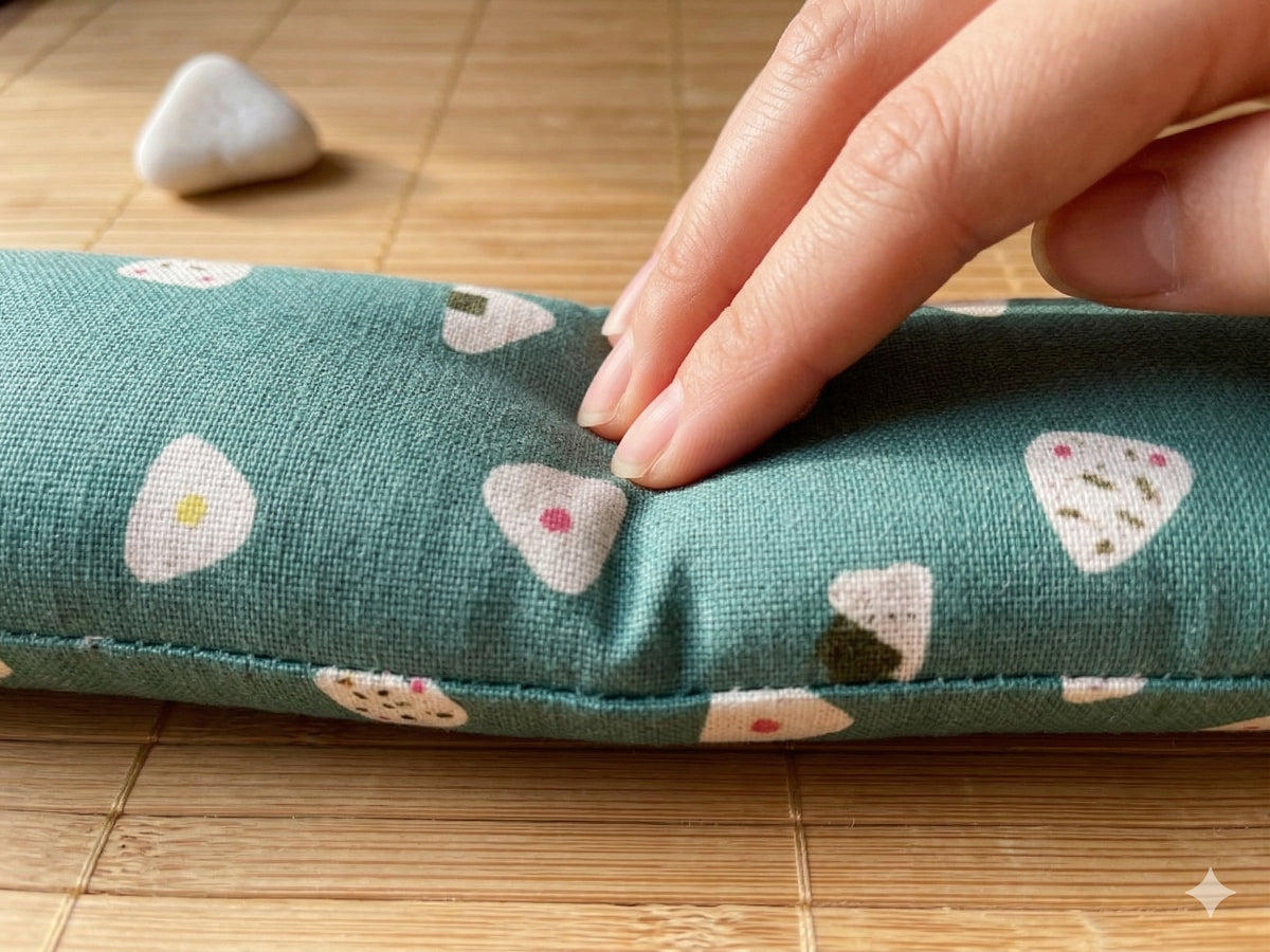 Fingers pressing into the onigiri wrist rest to show the buckwheat filling