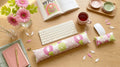 Pink floral keyboard and mouse wrist rests with a keyboard, pink flowers and tea on a wooden desk