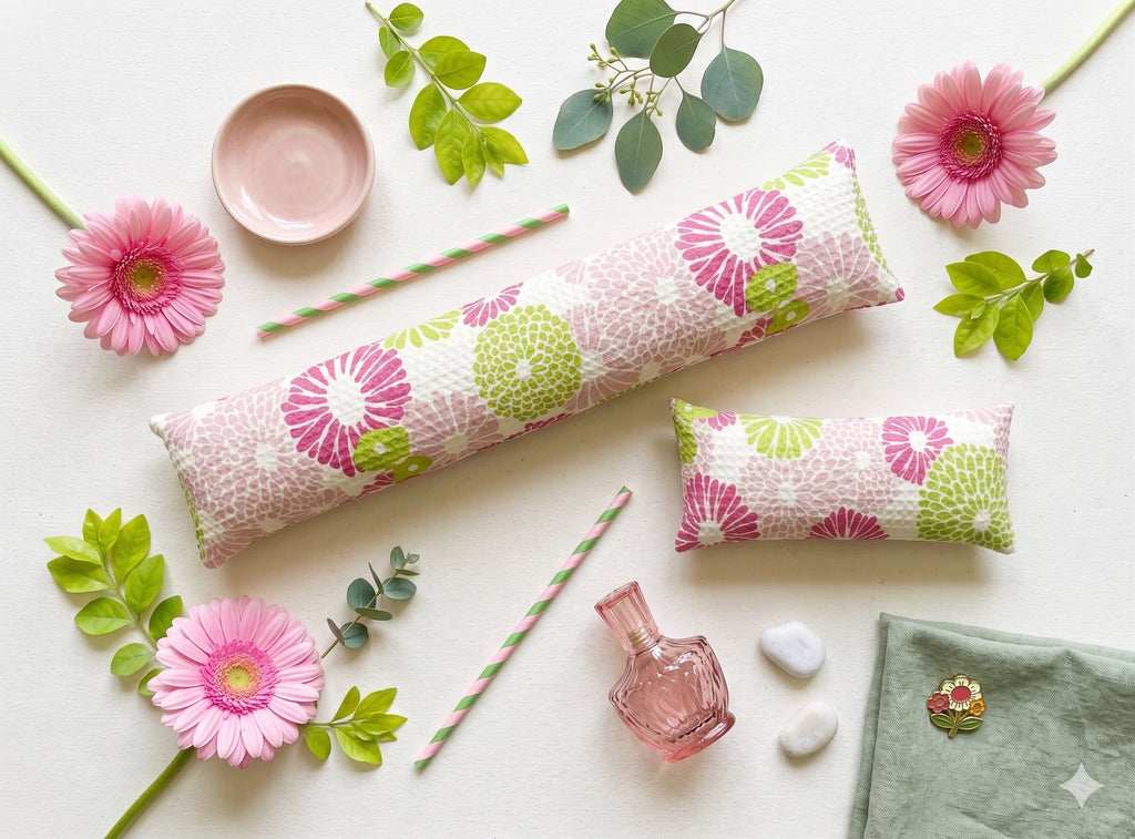 Pink floral wrist rest set laid flat among pink gerbera daisies and green leaves