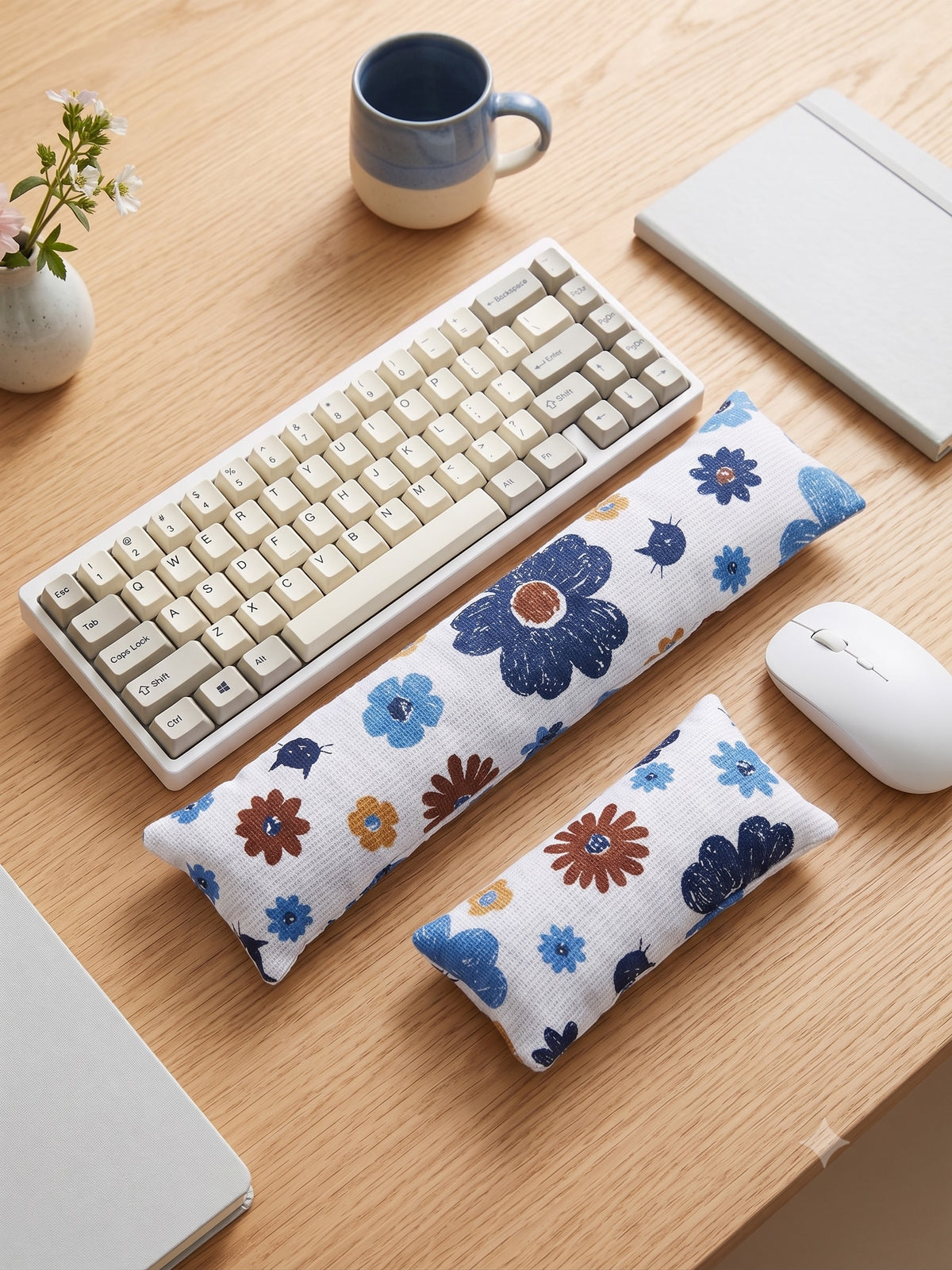 Blue retro floral cat keyboard and mouse wrist rests beside a keyboard on a wooden desk